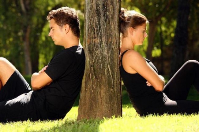 Мужчину и женщину, сидящих спиной к друг другу, разделяет дерево